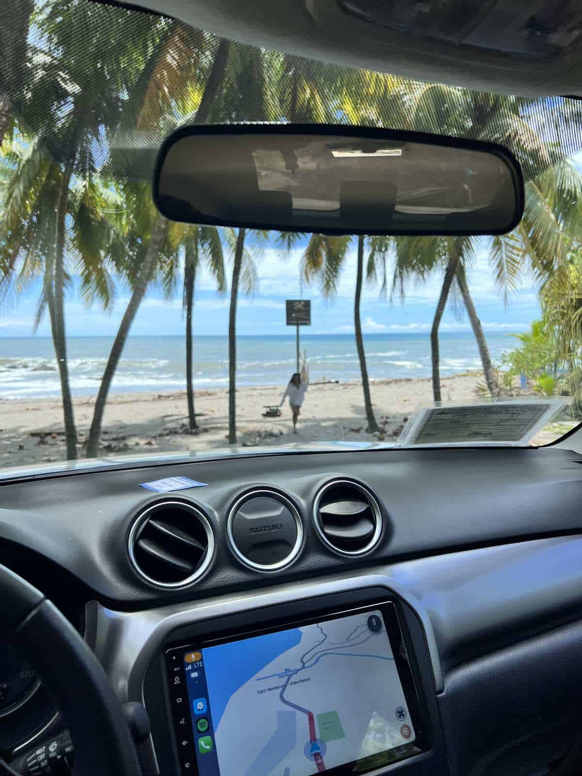 Photo form inside car, with beach in background through the windshield