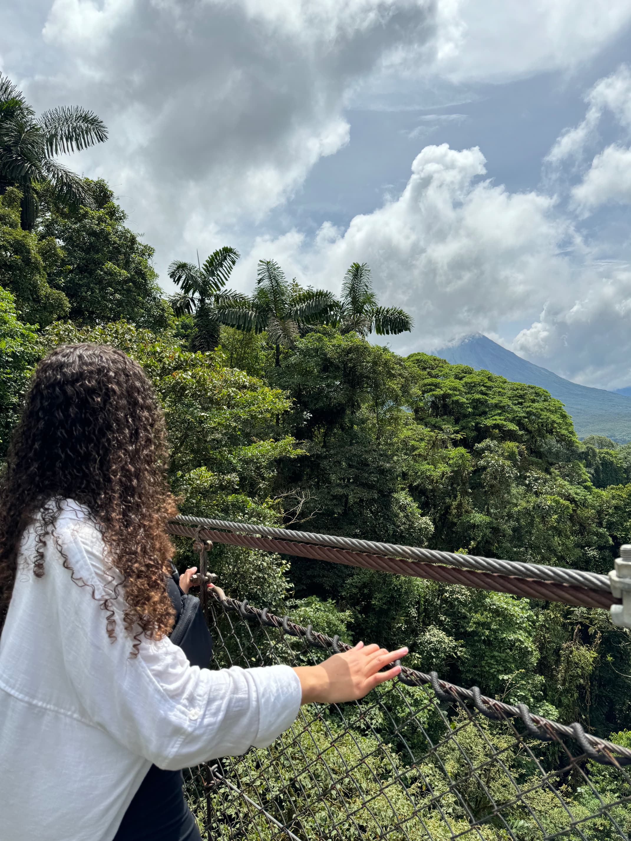 Girl with brown curly hair over looking volcano Arenal on 10 days in Costa Rica road trip.